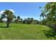 Lush backyard with expansive green lawn and picturesque water views with palm trees at 7214 Cloister Dr # 7214, Sarasota, FL 34231