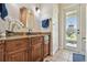 Bathroom featuring wooden vanity with granite countertop, decorative mirror, and door to the outside at 7264 Spencer Parrish Rd, Parrish, FL 34219
