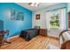 Bright bedroom with blue walls, hardwood floors, window with curtains and decorative wall art at 7264 Spencer Parrish Rd, Parrish, FL 34219