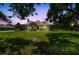 A cozy single-story home with a charming front porch, set against a vibrant sunset and lush green lawn at 7264 Spencer Parrish Rd, Parrish, FL 34219