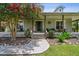Inviting front entrance with a covered porch, stone accents, mature landscaping, and a walkway to the front door at 7264 Spencer Parrish Rd, Parrish, FL 34219