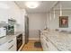 Galley kitchen featuring white cabinets, granite countertops, and stainless steel appliances at 750 N Tamiami Trl # 1005, Sarasota, FL 34236