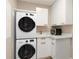 Bright laundry room with stacked washer and dryer, sink, and white cabinets at 750 N Tamiami Trl # 1005, Sarasota, FL 34236