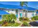 Bright white exterior with blue metal roof, lush tropical landscaping, and covered parking at 840 Audubon Dr, Bradenton, FL 34209