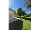 A backyard view shows the side of the home, a green lawn, scattered debris, and a few trees at 8409 Trionfo Ave, North Port, FL 34287