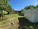 Rear view of a single-story house, featuring a large grassy yard and a storage shed at 8409 Trionfo Ave, North Port, FL 34287