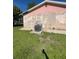 Side exterior view of the home with peeling paint, an air conditioning unit, and a green lawn at 8409 Trionfo Ave, North Port, FL 34287