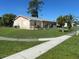 Side view of a single-story home with a grassy yard and a concrete sidewalk at 8409 Trionfo Ave, North Port, FL 34287