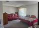 A living room showcasing a red sofa, bed, dresser, and a large window offering natural light at 8409 Trionfo Ave, North Port, FL 34287