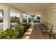Covered patio with chairs and table, adjacent to pool and landscaped with tropical plants and view of the beach at 1 Benjamin Franklin Dr # 93, Sarasota, FL 34236