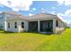 Back exterior view of home featuring a screened-in lanai and lush green lawn at 10177 Crystal Isle Cir, Sarasota, FL 34241