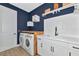 Modern laundry room with navy walls, white cabinets, and butcher block countertop at 10177 Crystal Isle Cir, Sarasota, FL 34241