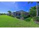 Beautiful backyard featuring lush green grass, meticulous landscaping, and a screened-in lanai at 10571 Old Grove Cir, Bradenton, FL 34212