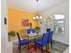 Dining room with a glass table, six blue chairs, colorful rug, and an eye-catching bright yellow accent wall at 10571 Old Grove Cir, Bradenton, FL 34212