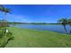 Expansive lake view from the lush green lawn, bordered by mature trees and palm trees at 10571 Old Grove Cir, Bradenton, FL 34212