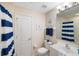 Bathroom featuring a toilet, sink, cabinet, framed mirror and blue-striped shower curtain at 150 L Pavia Blvd # 13, Venice, FL 34292