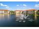 Scenic view of condo buildings surrounding a tranquil lake with a fountain under a blue sky at 150 L Pavia Blvd # 13, Venice, FL 34292
