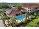 Aerial view of community pool and clubhouse nestled amongst palm trees and manicured lawns at 150 L Pavia Blvd # 13, Venice, FL 34292