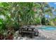 Charming backyard features a dining area near the pool, surrounded by lush tropical landscaping and privacy fencing at 1738 Siesta Dr, Sarasota, FL 34239
