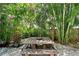 Landscaped backyard featuring a picnic table surrounded by lush greenery and trees at 1738 Siesta Dr, Sarasota, FL 34239