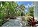Tranquil backyard with swimming pool, stone patio and tropical foliage at 1738 Siesta Dr, Sarasota, FL 34239