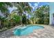 A tranquil pool is surrounded by tropical plants in the backyard, with a privacy fence at 1738 Siesta Dr, Sarasota, FL 34239