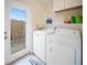 Bright laundry room featuring a washer, dryer, and access to the backyard at 204 21St Ne St, Bradenton, FL 34208