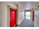 Well-lit hallway with a striking red door, leading to the outside balcony and community area at 210 3Rd W St # 8308, Bradenton, FL 34205