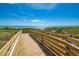 Accessible beach access ramp with wooden boardwalk leading towards the ocean under a partly cloudy sky at 237 Saxon Cir, Venice, FL 34293