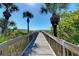 Inviting beach boardwalk with palm trees, leading to a beautiful beach and ocean view under a bright blue sky at 237 Saxon Cir, Venice, FL 34293
