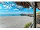 Beach view with sandy shore, clear blue water, a pier in the distance, and a sunny sky with some clouds at 237 Saxon Cir, Venice, FL 34293
