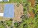 Aerial view of a single-story home with a metal roof, surrounded by greenery and a small waterway at 2523 Hagerick Ln, North Port, FL 34288