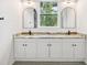 Bathroom featuring double vanity, dual mirrors, and black hardware fixtures at 2523 Hagerick Ln, North Port, FL 34288