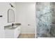 This bathroom is beautifully appointed with gray toned marble walk-in shower and granite countertops at 2523 Hagerick Ln, North Port, FL 34288