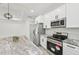 Modern kitchen featuring white cabinets, stainless steel appliances, and granite countertops with center island at 2523 Hagerick Ln, North Port, FL 34288