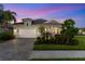 Charming single-Gathering home featuring a two-car garage, paver driveway, lush landscaping, and twilight sky at 2586 Wild Cherry Path, Sarasota, FL 34240