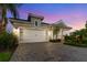 Charming single-Gathering home featuring a two-car garage, paver driveway, lush landscaping, and twilight sky at 2586 Wild Cherry Path, Sarasota, FL 34240