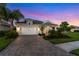 Charming one-story home with a paved driveway, two-car garage, and lush landscaping at sunset at 2586 Wild Cherry Path, Sarasota, FL 34240