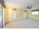 Spacious living room featuring light-colored walls and carpeting, a ceiling fan, and multiple windows at 307 Rubens Dr, Nokomis, FL 34275