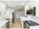 Modern kitchen features stainless steel appliances, white cabinetry with gold hardware and a light wood floor at 4250 Winfall Ave, North Port, FL 34286