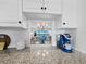 Detailed view from kitchen cabinet showing granite countertop, coffee maker, and dining area with water views at 4420 Exeter Dr # 303, Longboat Key, FL 34228