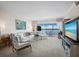 Bright living room with white sofa set, TV, art, and water view through large windows at 4420 Exeter Dr # 303, Longboat Key, FL 34228