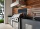 Gourmet outdoor kitchen with stainless steel grill, sleek countertops, and wood-paneled backsplash, perfect for entertaining at 4907 Topsail Dr, Nokomis, FL 34275