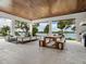 A covered outdoor living area features comfortable seating, a dining table, and stunning waterfront views at 4907 Topsail Dr, Nokomis, FL 34275