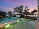 A gorgeous pool featuring stone steps with beautiful waterfront views and lush tropical landscaping at sunset at 4907 Topsail Dr, Nokomis, FL 34275