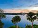 Scenic view of water and a distant home with palm trees in the foreground at sunset at 4907 Topsail Dr, Nokomis, FL 34275