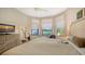 Relaxing bedroom featuring a decorative dresser, TV, seating area, neutral color palette, and large windows at 5234 Napoli Run, Bradenton, FL 34211