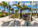 Outdoor seating area with a black swing, soft sand, and tropical palm trees for relaxing and enjoying the outdoors at 5234 Napoli Run, Bradenton, FL 34211