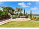 Outdoor patio with a variety of seating options on a well-maintained lawn, surrounded by palm trees and verdant landscaping at 5234 Napoli Run, Bradenton, FL 34211