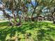 View of the single-story home from the front yard with mature trees providing shade at 5629 Boulder Blvd, Sarasota, FL 34233